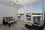 LOWER LEVEL BALCONY WITH SEATING, WALKOUT DOOR TO THE SIDEWALK LEADING TO THE SWIMMING POOL & A VIEW OF THE LAKE AND COMPLEX DOCKS